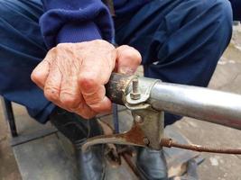 close-up da mão de um homem idoso com deficiência segurando a alça do triciclo foto