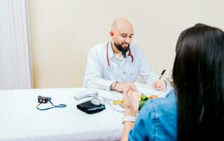 nutricionista homem dando consulta para mulher paciente dentro escritório, mulher paciente recebendo consulta a partir de nutricionista. sorridente nutricionista explicando para uma fêmea paciente foto