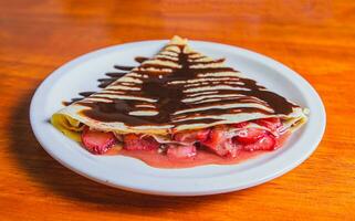 fechar acima do doce morango Tapioca com chocolate creme em de madeira mesa. Tapioca com chocolate creme e morango em de madeira mesa foto