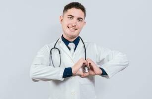 jovem latim médico fazer coração forma em isolado fundo. amigáveis médico fazer coração gesto com mãos isolado foto