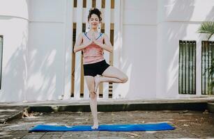 menina fazendo ioga vrikshasana ou árvore pose ao ar livre. jovem mulher fazendo vrikshasana ioga ao ar livre. relaxamento e vitalidade ioga conceito foto