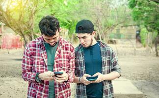 com ciumes amigo espionagem em dele amigos celular ao ar livre, amigo espionagem em dele amigo telefone. uma cara bisbilhotando em dele amigos telefone em a rua, conceito do com ciumes amigos com celular foto