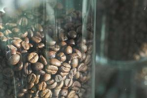 grãos de café torrados frescos em um frasco de vidro na cafeteria foto