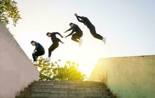 atleta homem fazendo Parkour pulando paredes. baixo ângulo do homem fazendo Parkour às pôr do sol. latim cara fazendo Parkour pulando paredes. foto