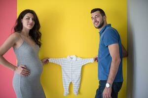 jovem casal segurando roupas de bebê foto