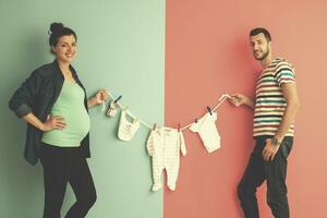 jovem casal segurando roupas de bebê foto