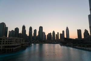 dubai cantando fontes às noite lago Visão entre arranha-céus. cidade Horizonte dentro crepúsculo moderno arquitetura dentro eua capital centro da cidade. foto