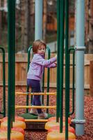 uma pequeno menina jogando dentro a parque. a conceito do família socializar dentro a parque. uma menina balanços em uma balanço, tocam criativo jogos foto