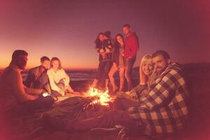 casal curtindo com amigos ao pôr do sol na praia foto