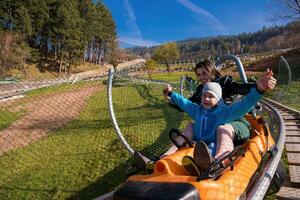 jovem mãe e filho dirigindo alpino montanha-russa foto