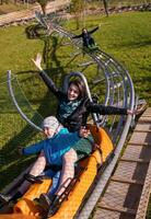 jovem mãe e filho dirigindo alpino montanha-russa foto