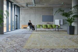 homem de negocios dentro uma cadeira de rodas dentro uma moderno escritório solitário depois de uma ocupado dia foto