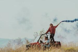 grupo do jovem feliz animado pessoas tendo Diversão desfrutando lindo ensolarado dia segurando colorida tochas enquanto dirigindo uma fora estrada buggy carro em montanha natureza. foto