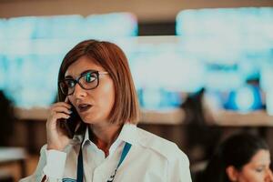 fêmea segurança guarda operador falando em a telefone enquanto trabalhando às posto de trabalho com múltiplo monitores segurança guardas trabalhando em múltiplo monitores foto