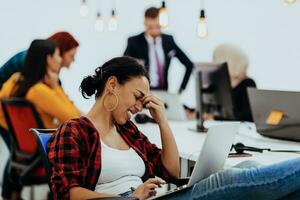 cansado empresária sentado dentro a escritório e trabalhando em dela computador portátil foto