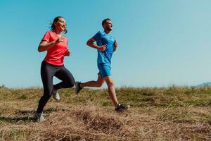 casal desfrutando dentro uma saudável estilo de vida enquanto corrida em uma país estrada através a lindo ensolarado floresta, exercício e ginástica conceito foto