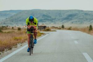 cheio comprimento retrato do a ativo triatleta dentro roupa de esporte e com uma protetora capacete equitação uma bicicleta. seletivo foco foto