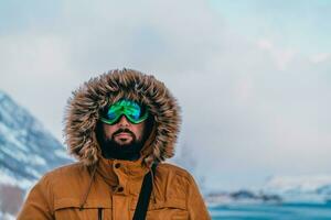 Tiros na Cabeça foto do uma homem dentro uma frio Nevado área vestindo uma Grosso Castanho inverno jaqueta, neve óculos e luvas. vida dentro frio regiões do a país.