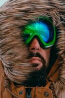 Tiros na Cabeça foto do uma homem dentro uma frio Nevado área vestindo uma Grosso Castanho inverno jaqueta, neve óculos e luvas. vida dentro frio regiões do a país.