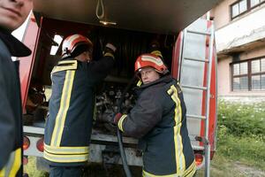 grupo do fogo lutadores em pé confiante depois de uma bem feito resgate Operação. bombeiros pronto para emergência serviço. foto