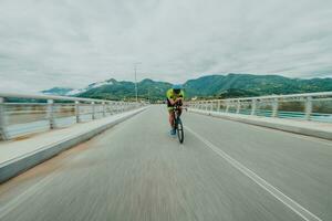 cheio comprimento retrato do a ativo triatleta dentro roupa de esporte e com uma protetora capacete equitação uma bicicleta. seletivo foco foto