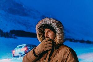 cabeça tiro do uma homem dentro uma frio Nevado área vestindo uma Grosso Castanho inverno jaqueta, neve óculos e luvas em uma frio escandinavo noite. vida dentro a frio regiões do a país. foto