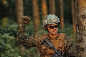 moderno guerra soldado Policial é mostrando tático mão sinais para silenciosamente dar ordens e alertas para pelotão equipe floresta ambiente foto