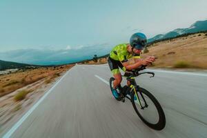 cheio comprimento retrato do a ativo triatleta dentro roupa de esporte e com uma protetora capacete equitação uma bicicleta. seletivo foco foto