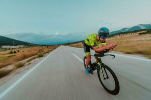 cheio comprimento retrato do a ativo triatleta dentro roupa de esporte e com uma protetora capacete equitação uma bicicleta. seletivo foco foto