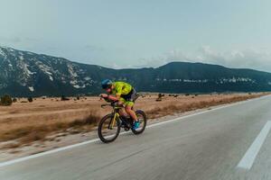 cheio comprimento retrato do a ativo triatleta dentro roupa de esporte e com uma protetora capacete equitação uma bicicleta. seletivo foco foto