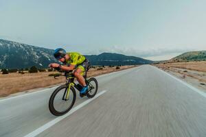 cheio comprimento retrato do a ativo triatleta dentro roupa de esporte e com uma protetora capacete equitação uma bicicleta. seletivo foco foto