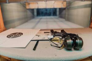 tiroteio equipamento dentro frente do a alvo. pistola, óculos e fones de ouvido em a mesa do uma moderno tiroteio alcance foto