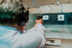 uma homem práticas tiroteio uma pistola dentro uma tiroteio alcance enquanto vestindo protetora fones de ouvido foto