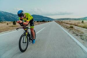 cheio comprimento retrato do a ativo triatleta dentro roupa de esporte e com uma protetora capacete equitação uma bicicleta. seletivo foco foto