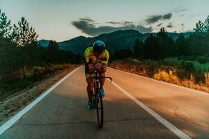 noite dirigir. cheio comprimento retrato do a ativo triatleta dentro roupa de esporte e com uma protetora capacete equitação uma bicicleta dentro noite tempo.. seletivo foco foto