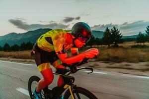 noite dirigir. cheio comprimento retrato do a ativo triatleta dentro roupa de esporte e com uma protetora capacete equitação uma bicicleta dentro noite tempo.. seletivo foco foto