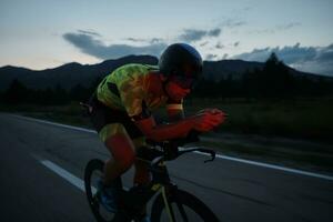 atleta de triatlo andando de bicicleta à noite foto