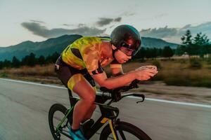 noite dirigir. cheio comprimento retrato do a ativo triatleta dentro roupa de esporte e com uma protetora capacete equitação uma bicicleta dentro noite tempo.. seletivo foco foto