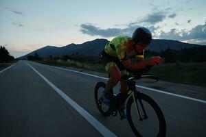 atleta de triatlo andando de bicicleta à noite foto