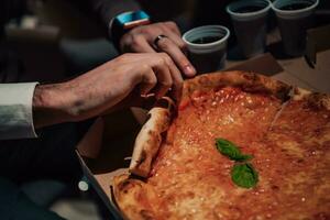 fechar acima foto do ocupado pessoas comendo pizza dentro a escritório durante uma pausa