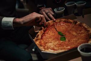 fechar acima foto do ocupado pessoas comendo pizza dentro a escritório durante uma pausa