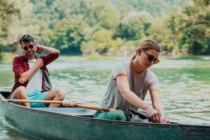casal aventureiro explorador amigos estão canoagem dentro uma selvagem rio cercado de a lindo natureza foto