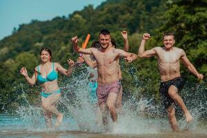 uma grupo do diverso jovem pessoas tendo Diversão juntos Como elas corre ao longo a rio e jogar água jogos foto