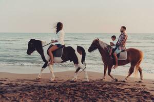 a família passa o tempo com seus filhos enquanto andam a cavalo juntos em uma praia de areia. foco seletivo foto