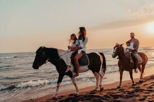 a família passa o tempo com seus filhos enquanto andam a cavalo juntos em uma praia de areia. foco seletivo foto