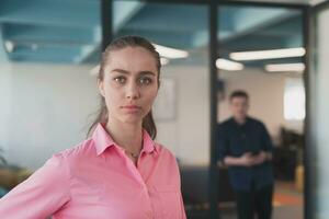 retrato do jovem sorridente o negócio mulher dentro criativo aberto espaço coworking comece escritório. bem sucedido empresária em pé dentro escritório com copyspace. colegas de trabalho trabalhando dentro fundo. foto