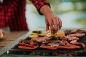 uma homem preparando uma delicioso jantar para dele amigos quem estão tendo Diversão de a rio dentro natureza foto