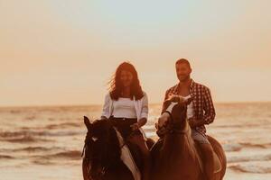 um casal apaixonado em roupas de verão, montando um cavalo em uma praia ao pôr do sol. mar e pôr do sol ao fundo. foco seletivo foto