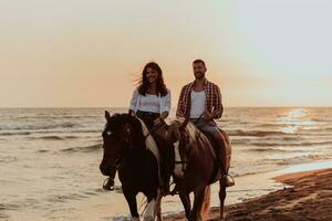 um casal apaixonado em roupas de verão, montando um cavalo em uma praia ao pôr do sol. mar e pôr do sol ao fundo. foco seletivo foto