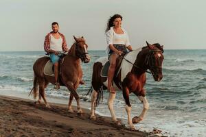 um casal apaixonado em roupas de verão, montando um cavalo em uma praia ao pôr do sol. mar e pôr do sol ao fundo. foco seletivo foto